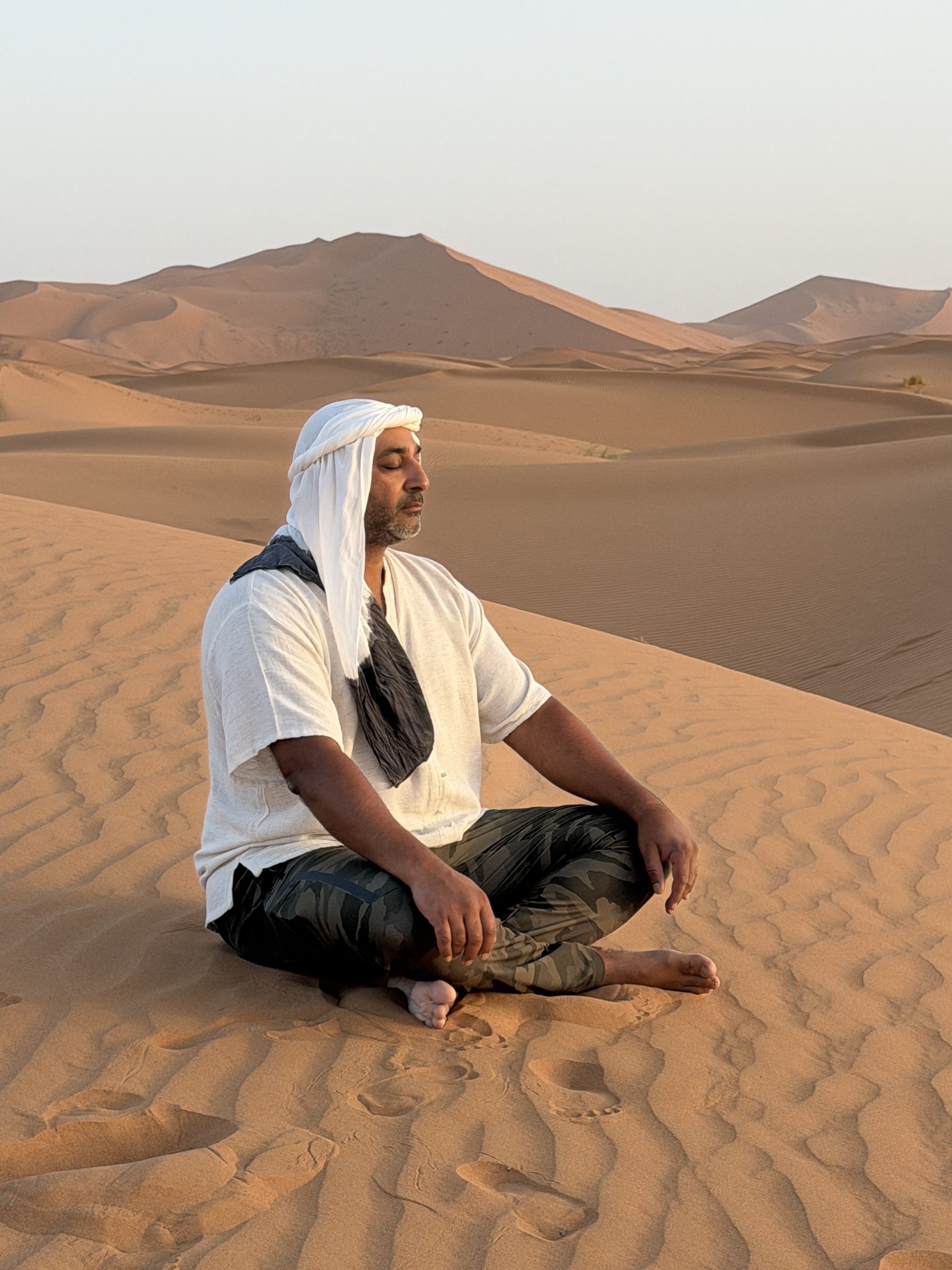 Peter Johal sitting on a Sahara dune at sunrise